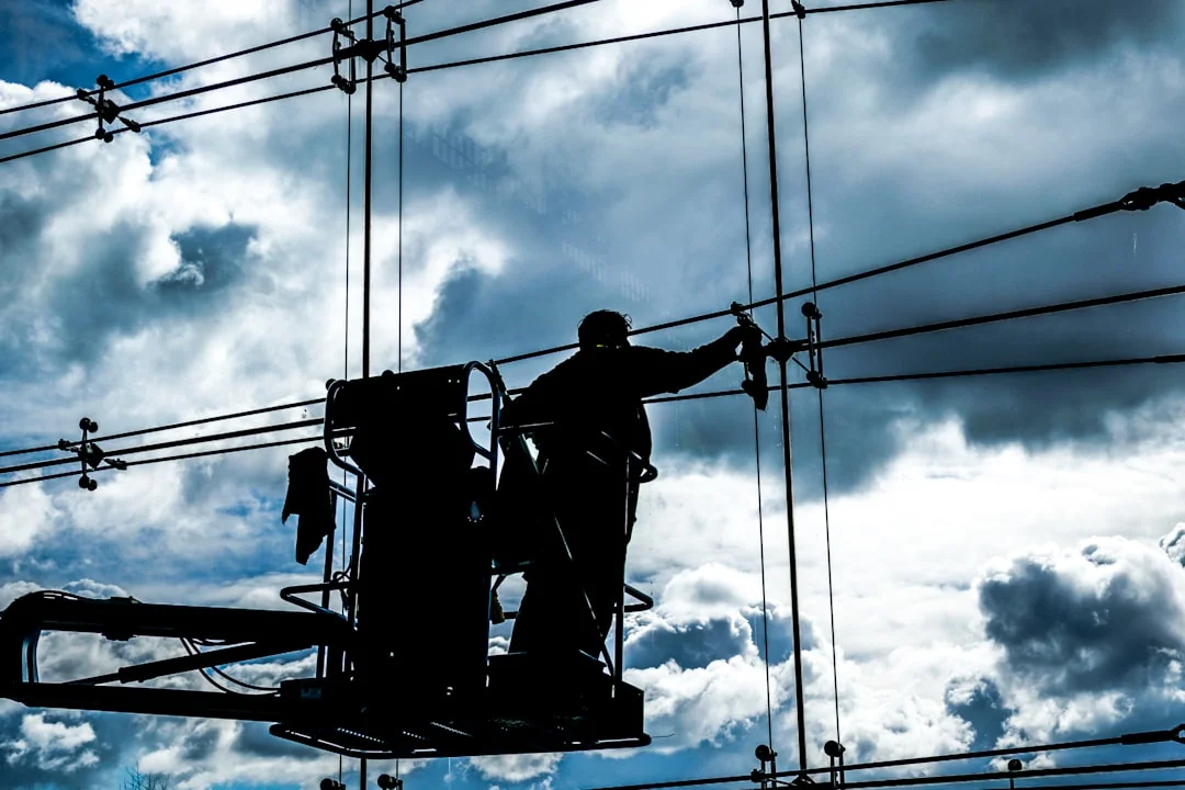 A worker cleaning skyscraper windows with a harness in an urban setting.
